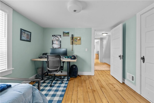 office featuring hardwood / wood-style floors, visible vents, baseboards, and plenty of natural light
