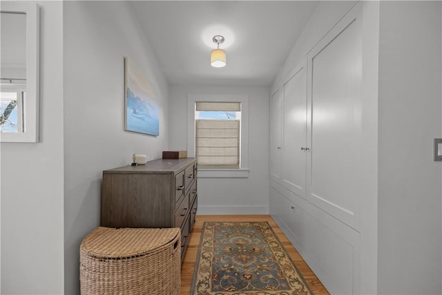 hall with light wood-type flooring and baseboards