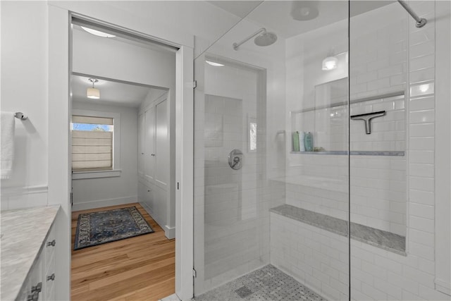 bathroom featuring wood finished floors, vanity, and a stall shower