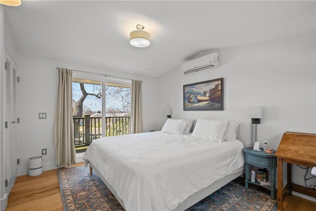 bedroom featuring light wood finished floors, vaulted ceiling, access to outside, and a wall mounted air conditioner
