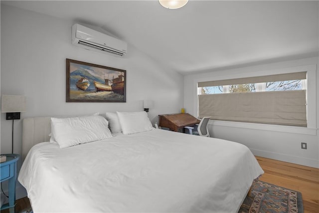 bedroom with lofted ceiling, wood finished floors, and an AC wall unit