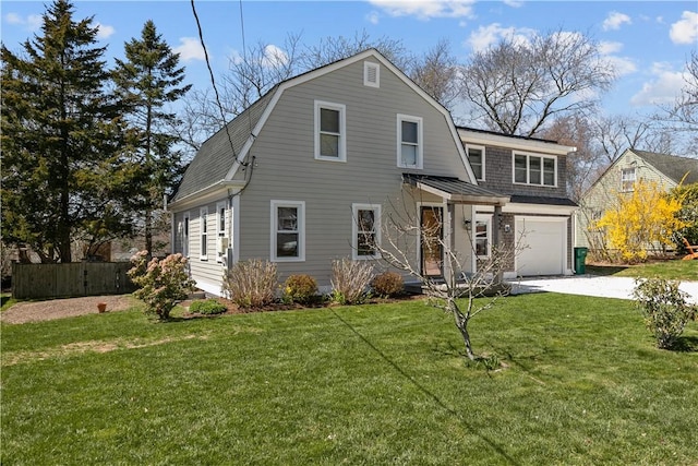 colonial inspired home with a front lawn, concrete driveway, fence, a garage, and a gambrel roof