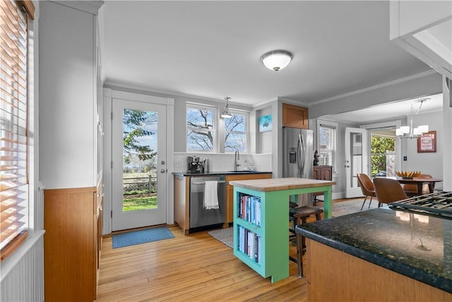 kitchen featuring a healthy amount of sunlight, stainless steel appliances, light wood-type flooring, and a sink