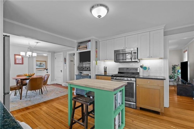 kitchen with wooden counters, an inviting chandelier, backsplash, ornamental molding, and appliances with stainless steel finishes