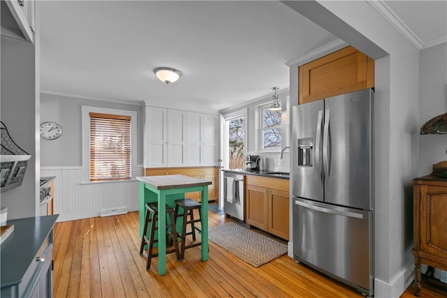 kitchen featuring stainless steel appliances, a sink, wainscoting, visible vents, and light wood-style floors