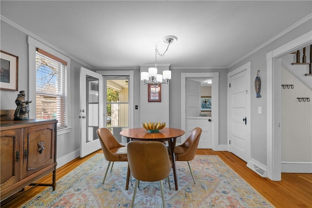 dining area featuring ornamental molding, baseboards, a notable chandelier, and light wood-style floors