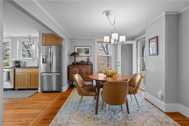 dining space featuring ornamental molding, a healthy amount of sunlight, a chandelier, and light wood finished floors