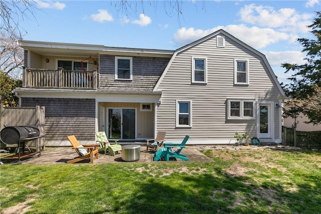 rear view of house featuring a yard, a gambrel roof, a balcony, and fence