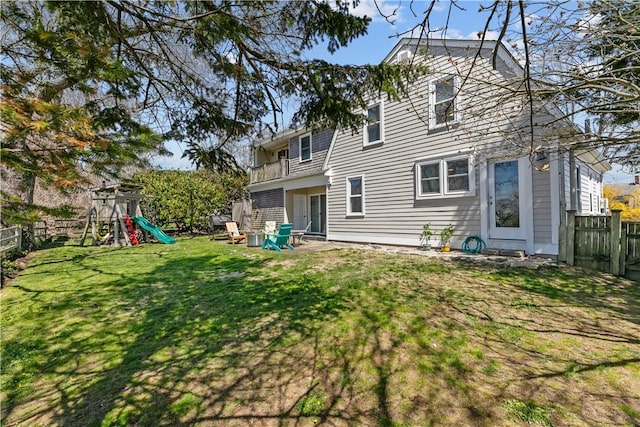 back of house featuring a lawn, a fenced backyard, and a playground
