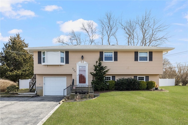 bi-level home featuring an attached garage, a front lawn, aphalt driveway, and fence
