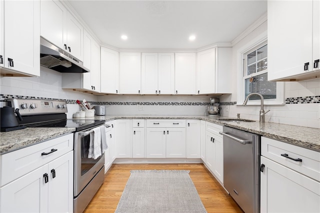 kitchen featuring white cabinets, stainless steel appliances, a sink, tasteful backsplash, and under cabinet range hood