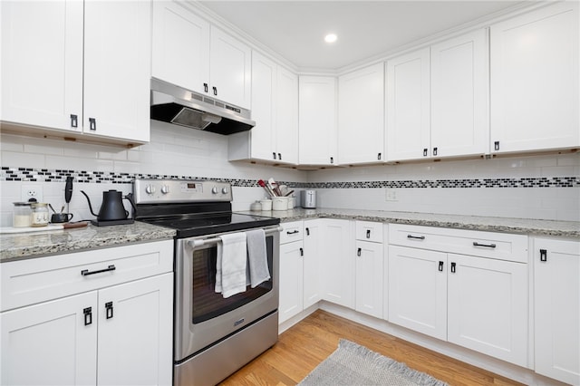 kitchen with white cabinets, under cabinet range hood, light wood-style floors, tasteful backsplash, and electric range