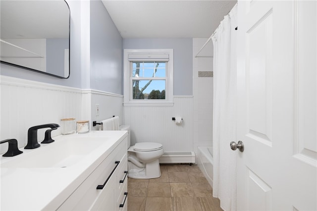 bathroom featuring a wainscoted wall, toilet, vanity, shower / tub combo with curtain, and baseboard heating