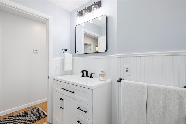 bathroom with wood finished floors, a wainscoted wall, and vanity