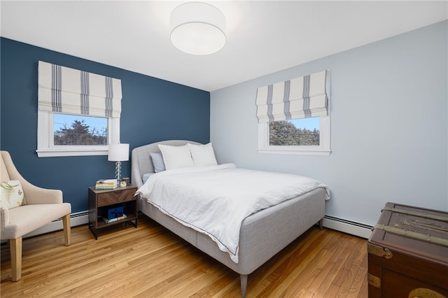 bedroom with light wood-type flooring and baseboard heating
