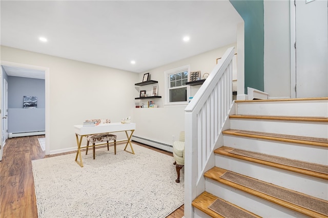 staircase with baseboard heating, a baseboard radiator, wood finished floors, and recessed lighting