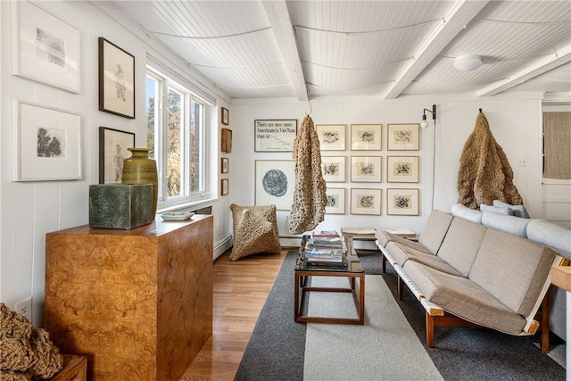 living area with a baseboard heating unit, wood finished floors, and beamed ceiling