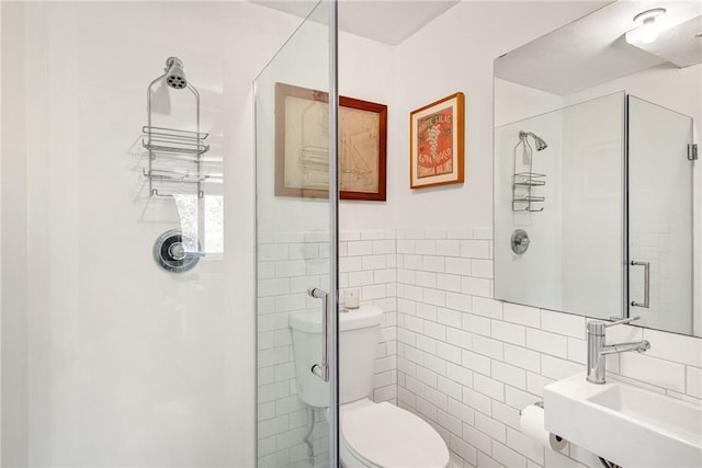full bath featuring toilet, a stall shower, a sink, and tile walls