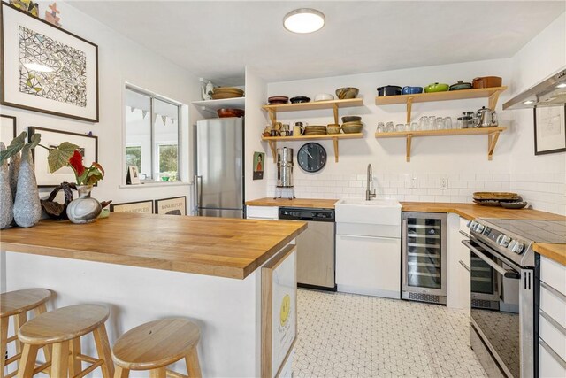 kitchen featuring wine cooler, open shelves, a sink, butcher block countertops, and appliances with stainless steel finishes