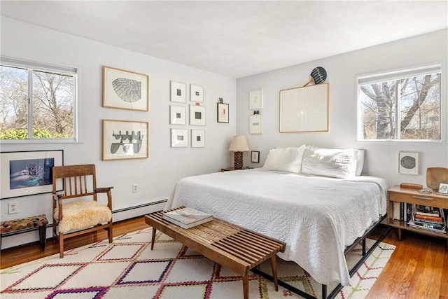 bedroom with baseboard heating and wood finished floors
