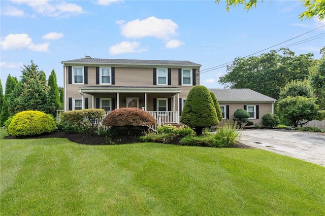 colonial house featuring a front lawn and covered porch