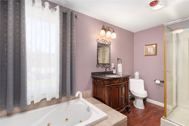 full bath featuring a stall shower, toilet, wood finished floors, a tub with jets, and vanity
