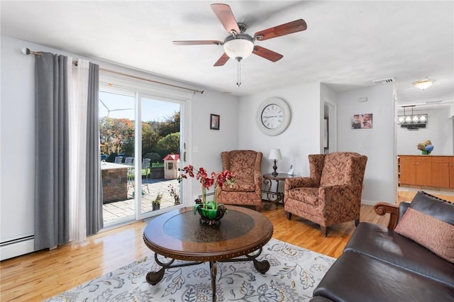 living area featuring light wood-style flooring, visible vents, and ceiling fan with notable chandelier