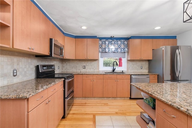 kitchen featuring light stone counters, open shelves, a sink, light wood-style floors, and appliances with stainless steel finishes