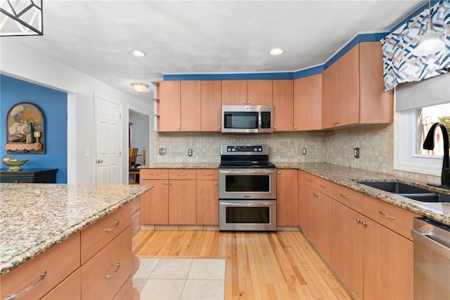 kitchen featuring stainless steel appliances, a sink, light wood-style floors, decorative backsplash, and open shelves
