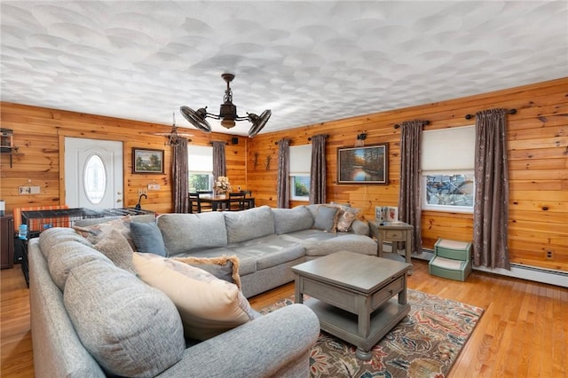 living room with a ceiling fan, wooden walls, and light wood-type flooring
