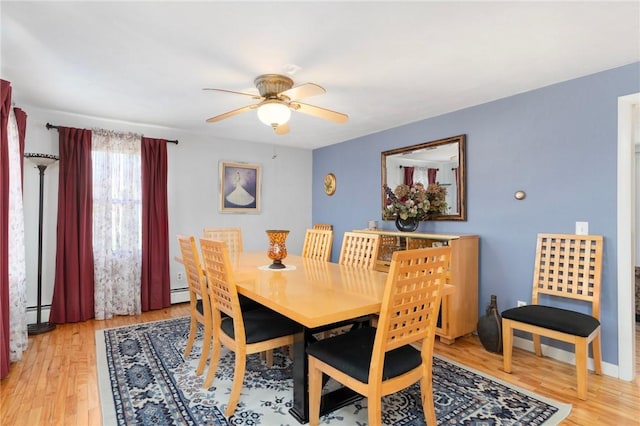dining room with baseboard heating, light wood-style floors, and ceiling fan