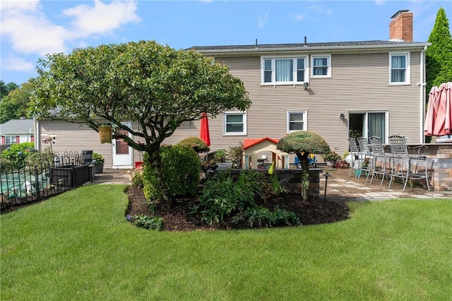 back of house with fence, a chimney, a yard, and a patio