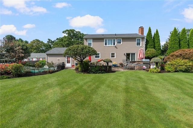 rear view of property featuring a lawn and a chimney