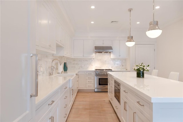 78 Rhode Island Ave Unit 8, Newport, RI 02840 - kitchen with high end stove, a sink, under cabinet range hood, a center island, and light countertops