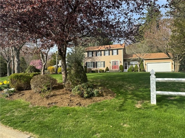 colonial house featuring driveway, a front lawn, and a garage