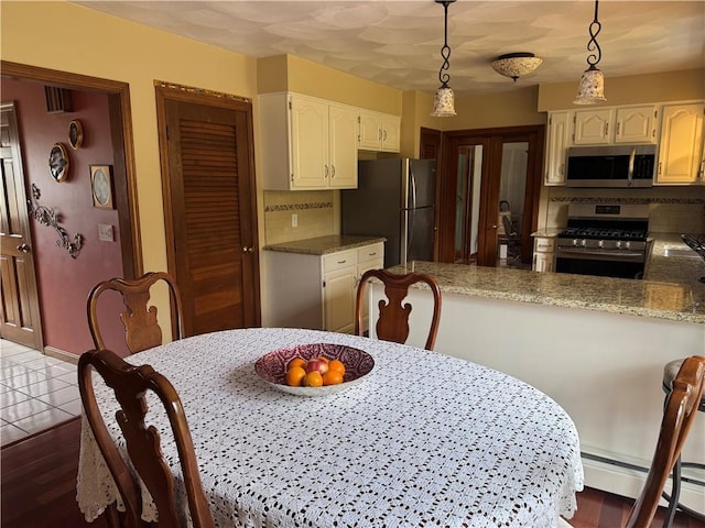 kitchen with a peninsula, hanging light fixtures, appliances with stainless steel finishes, baseboard heating, and white cabinetry