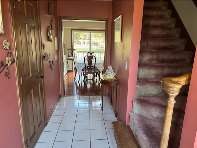 interior space with stairway, baseboards, and light tile patterned floors