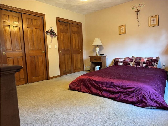carpeted bedroom with a baseboard heating unit and two closets