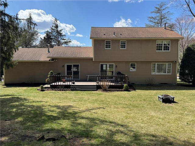 back of property with a lawn, a deck, and an outdoor fire pit