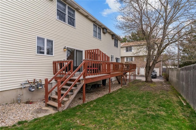 rear view of house featuring fence, a lawn, stairs, and a deck