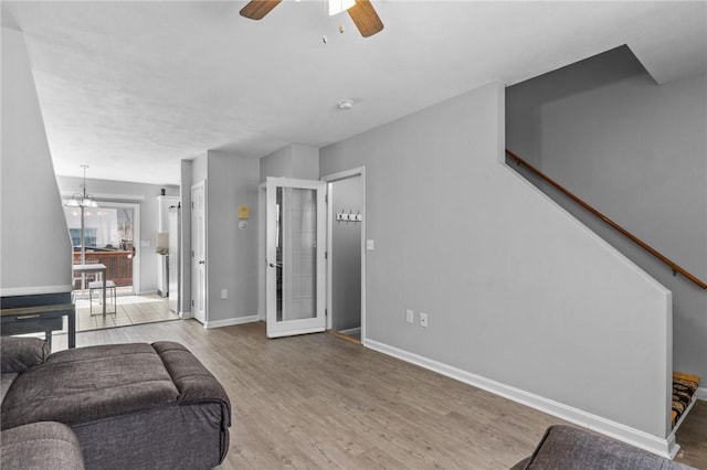 living room featuring stairway, ceiling fan, baseboards, and wood finished floors
