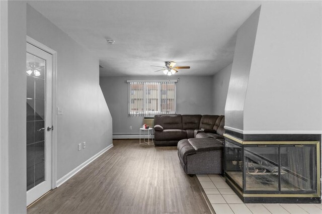 living room with a baseboard radiator, baseboards, wood finished floors, and ceiling fan