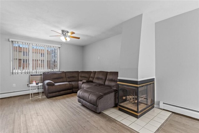 living area featuring a baseboard heating unit, an AC wall unit, wood finished floors, ceiling fan, and a baseboard radiator
