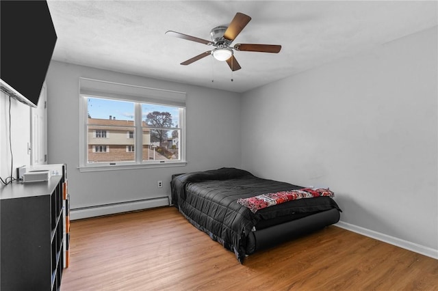 bedroom featuring a baseboard radiator, light wood-style floors, baseboards, and ceiling fan