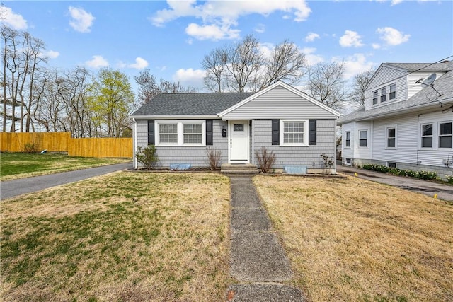 bungalow-style home featuring a front lawn, fence, and roof with shingles