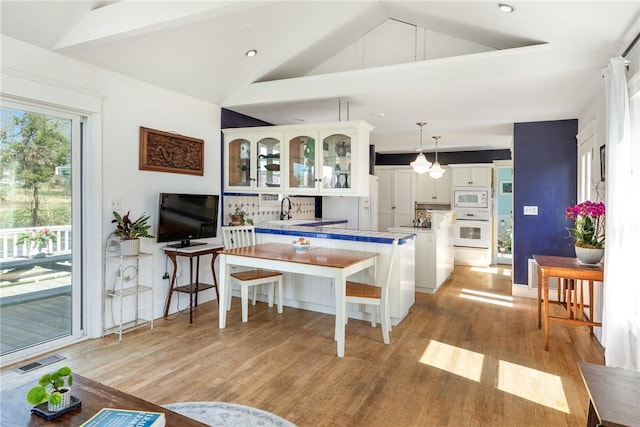 kitchen featuring light wood-style flooring, visible vents, white cabinetry, glass insert cabinets, and white appliances