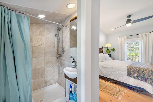 full bathroom featuring wood finished floors, a sink, connected bathroom, and a tile shower