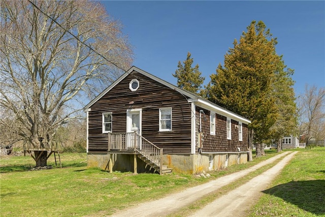 view of front of property with dirt driveway and a front yard