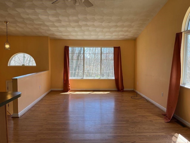 interior space with ceiling fan, baseboards, an ornate ceiling, and wood finished floors