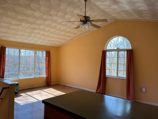 spare room with vaulted ceiling, a ceiling fan, and baseboards